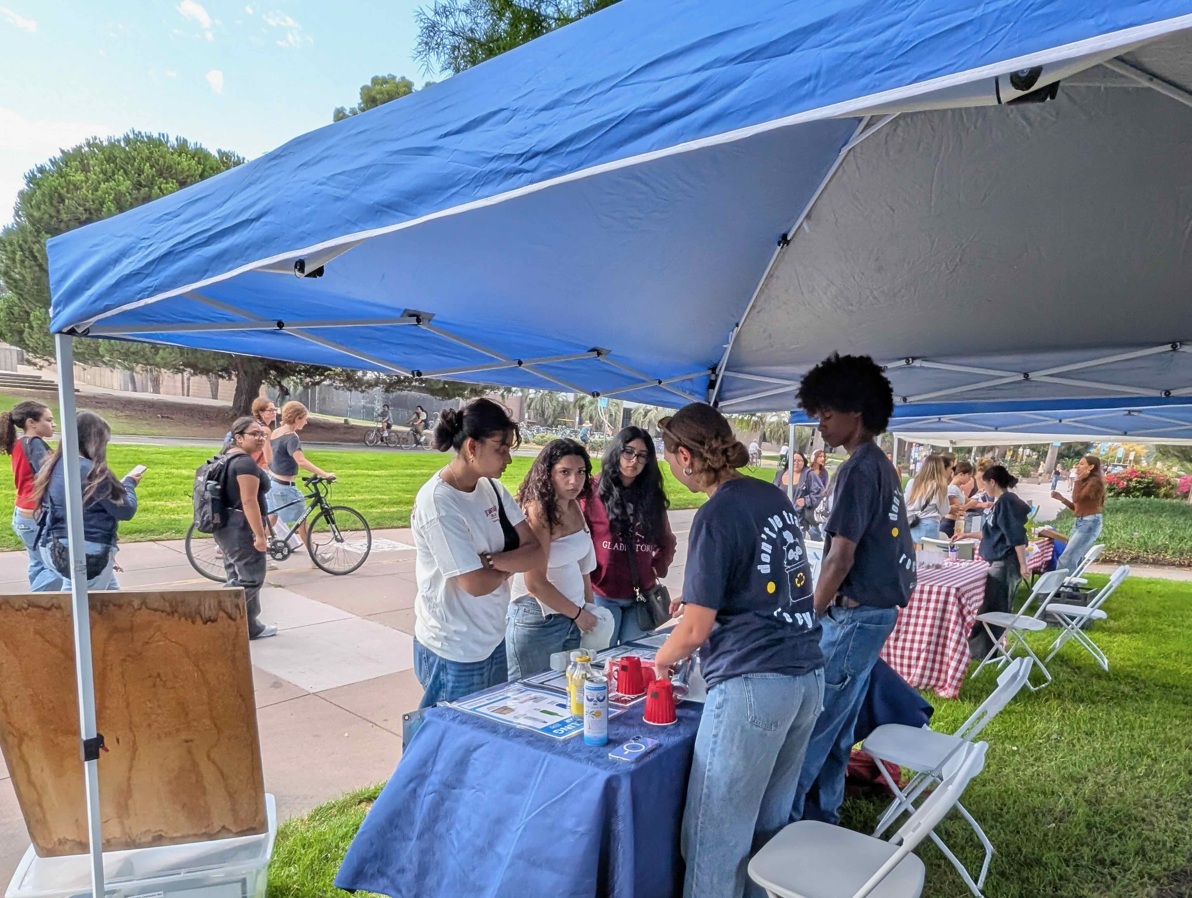 Photo of a two student workers at a CFHL event talking with passersby. 