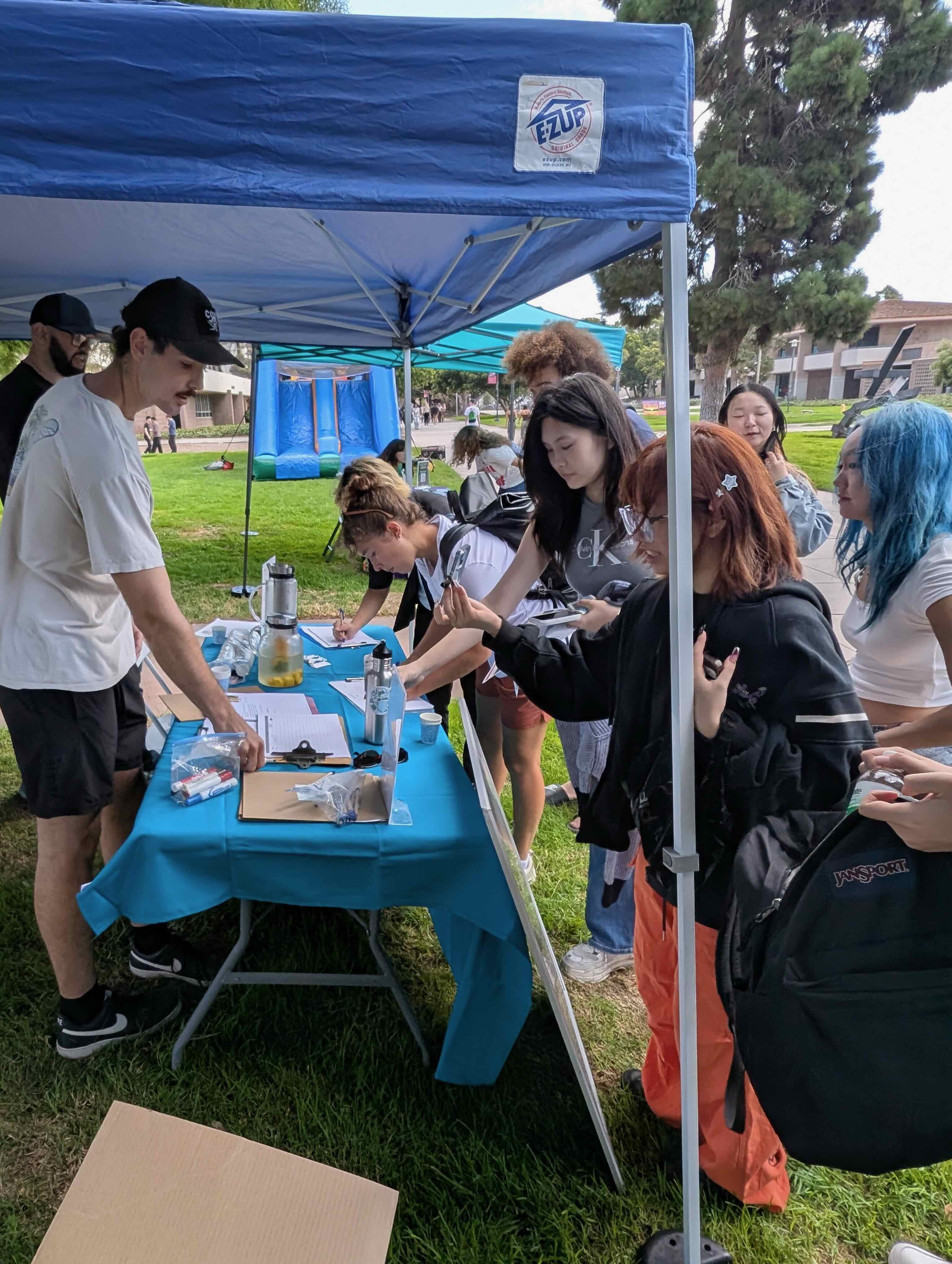 Photo of a student intern at a CFHL event talking with passersby. 
