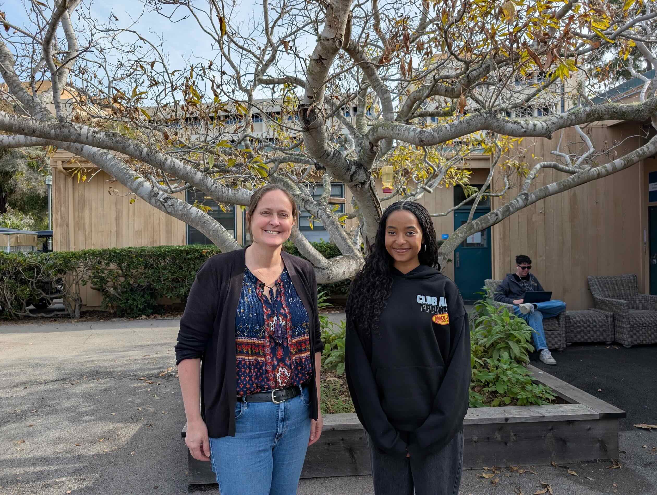 Two people standing outdoors posing for a picture. 